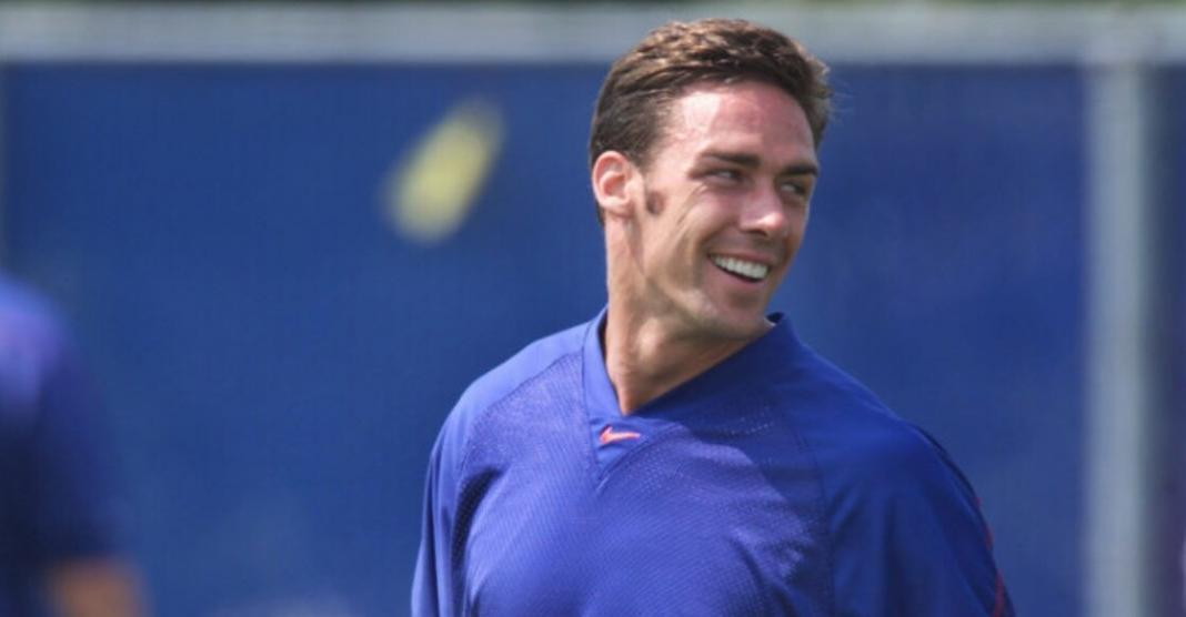 Jason Sehorn in blue t shirt smiling sideways with blue background