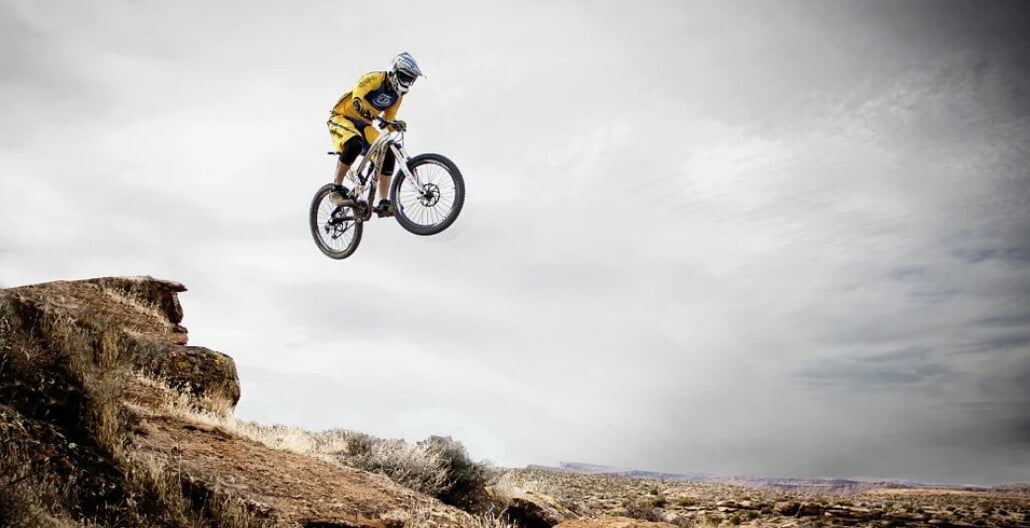 a person riding BMX bike on a mountain place with blue clear sky in the background