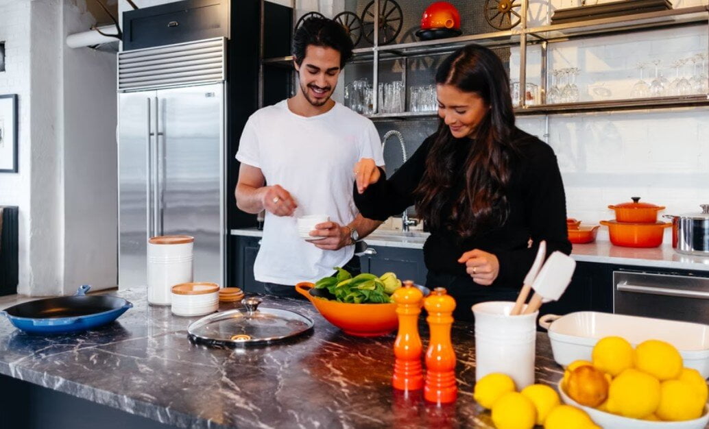 a man helping her wife in kitchen and pampering to show kindness and love