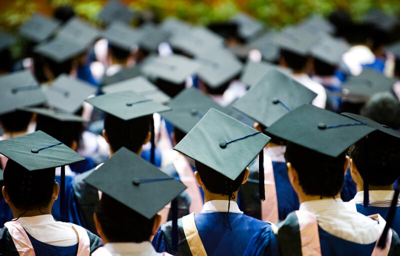 a number of students with their graduation caps in black color on a graduation day