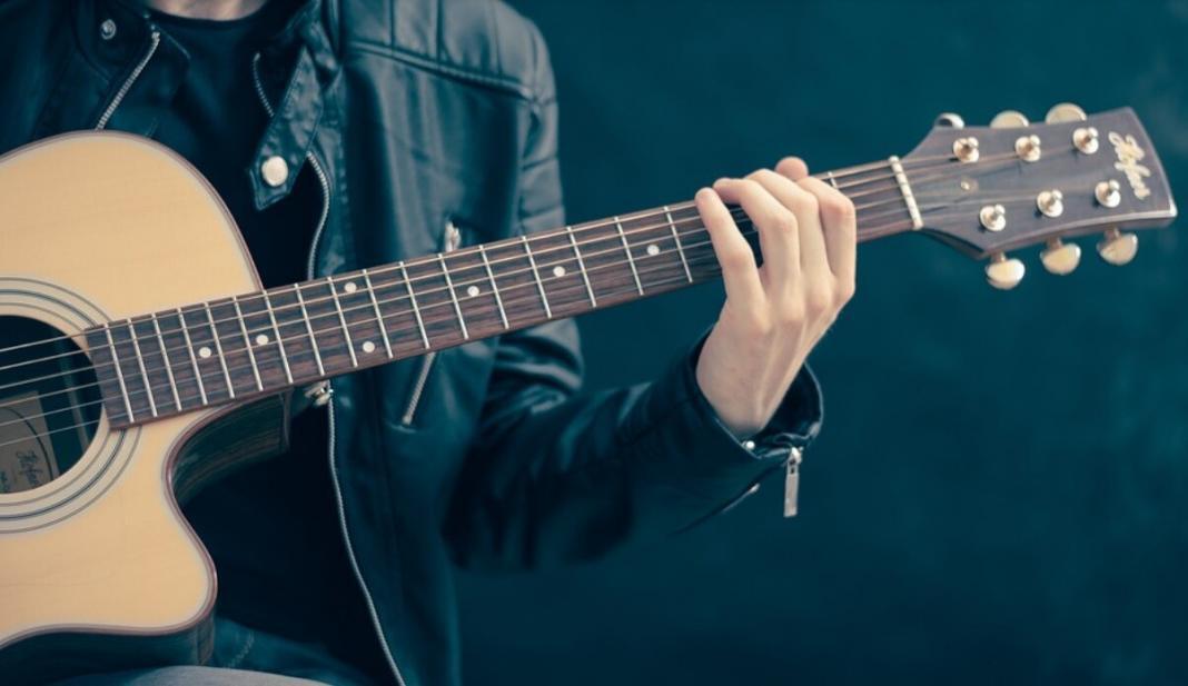 a person playing songs using his guitar with black background
