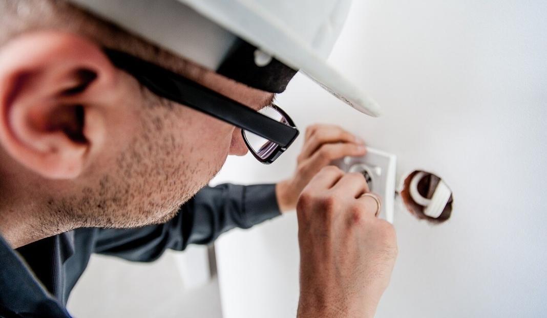 man repairing electric switch with his protective helmet
