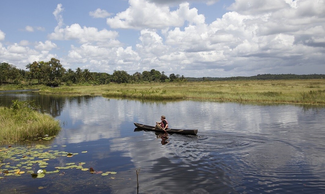 a person sailing in boat in Guyana with clear sky and clouds