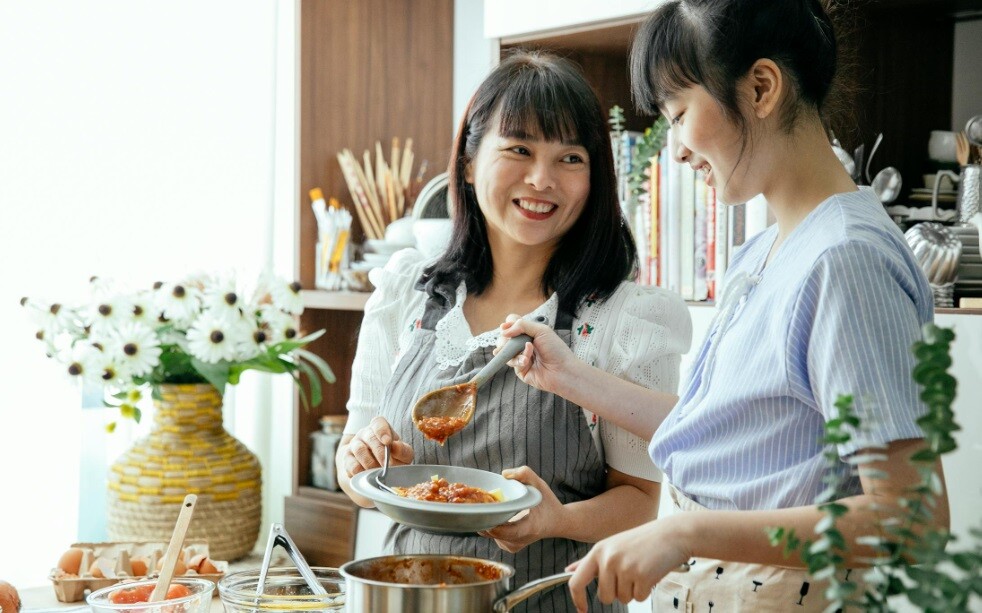 two young ladies standing in an open kitchen and talking about apron