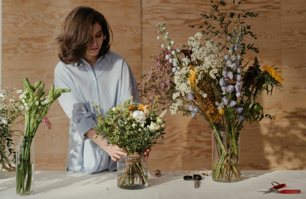 a lady arranging flowers on a table for decoration