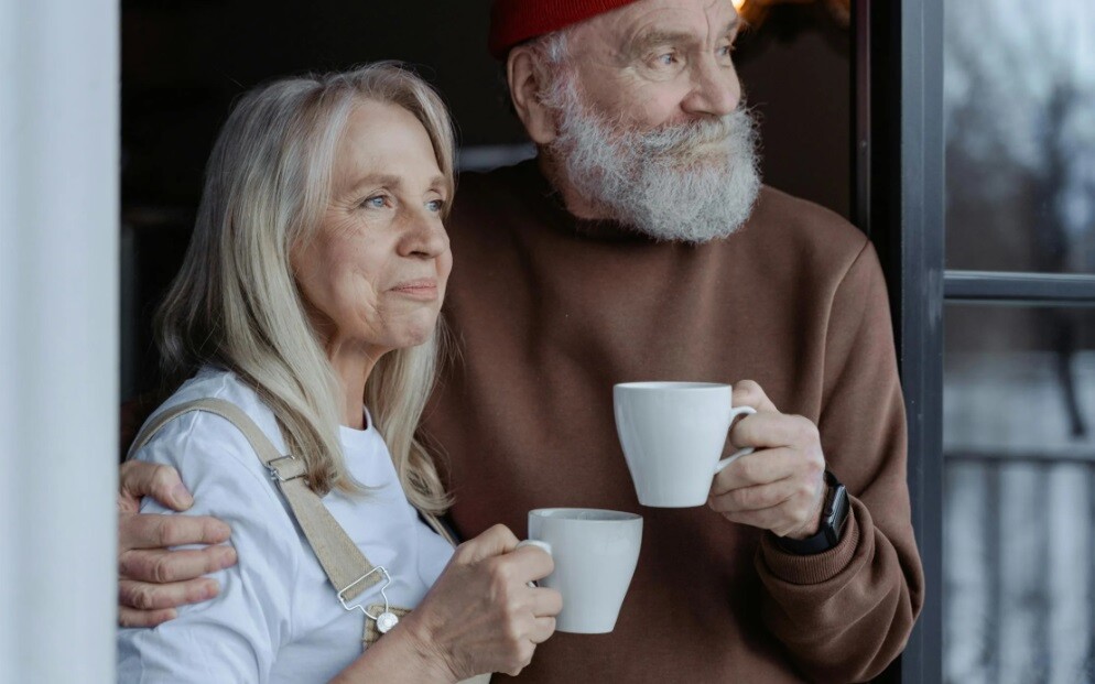 old couple holding each other and having a cup of coffee showing their retirals