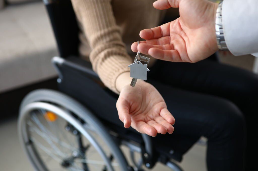 a person handing over a key to the person in wheechair
