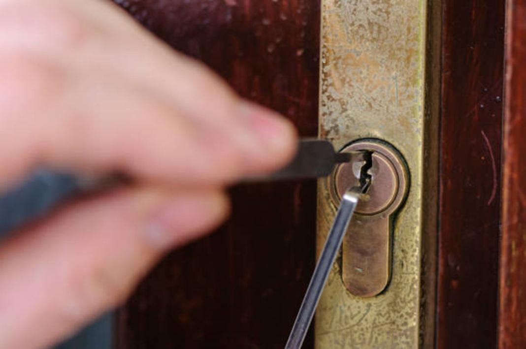 a man piercing into the hole of the door with a pin to unlock