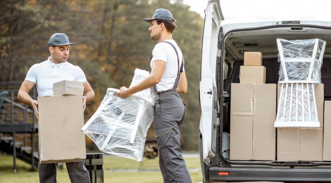 two people packing household items in cardboard boxes 