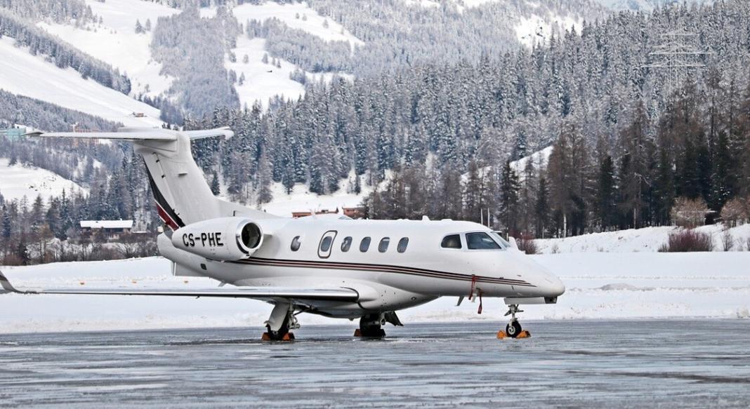 a white private jet in a on the ground with mountains behind the jet