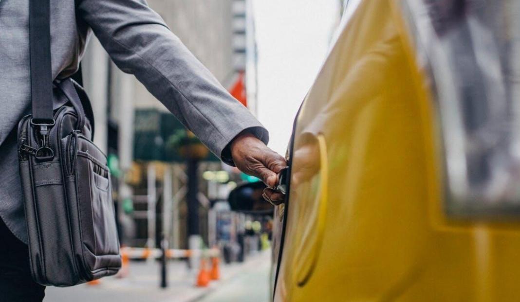a person opening the door of a taxi travel