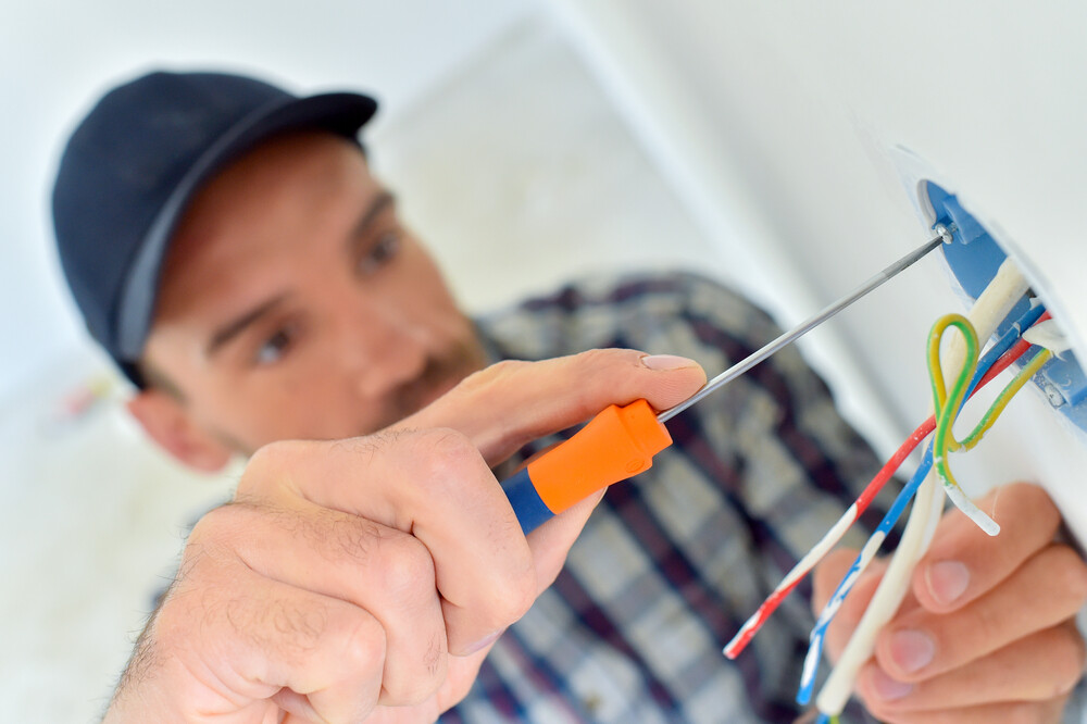 a man with cap trying to repair an electrical component