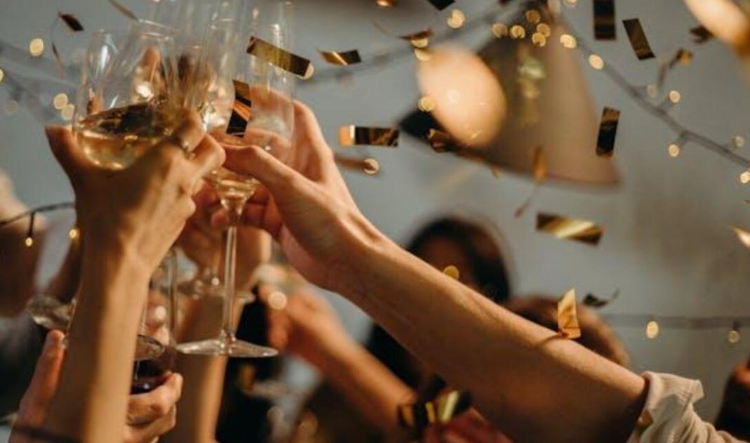 people are raising their hands in cheer over a cup of wines. They are making cheers for partying