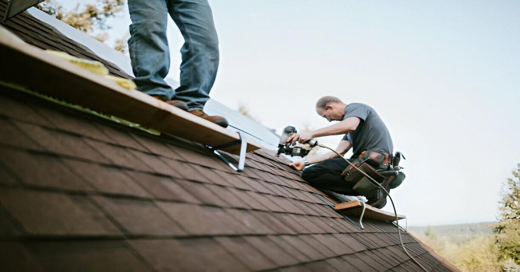 two people standing on the roof top and doing repair