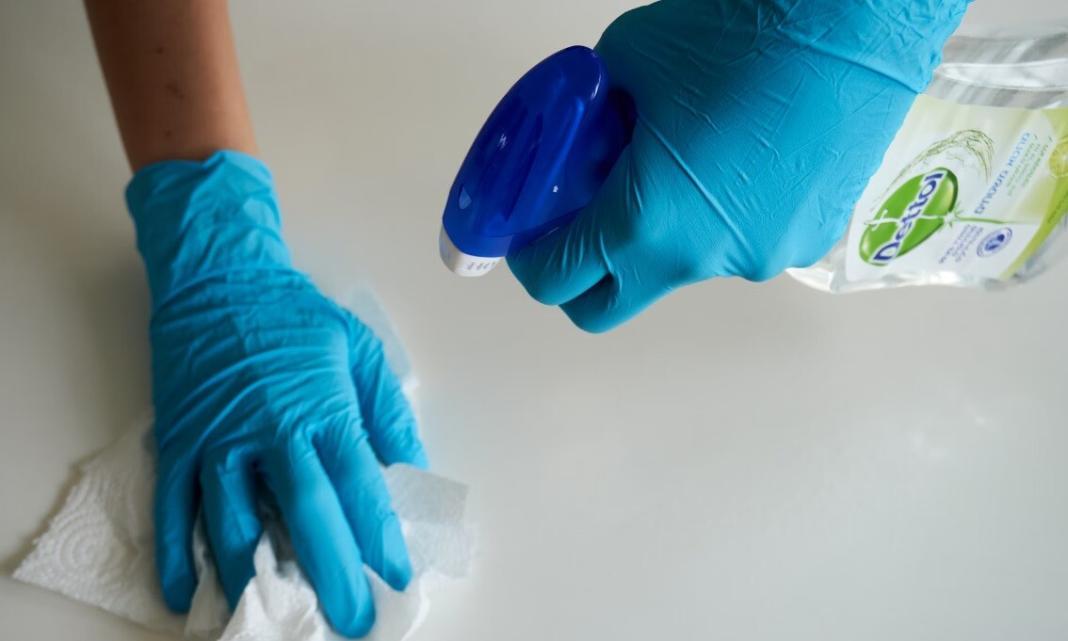 two hands with gloves cleaning the floor with antiseptic liquid signifying zero waste cleaning