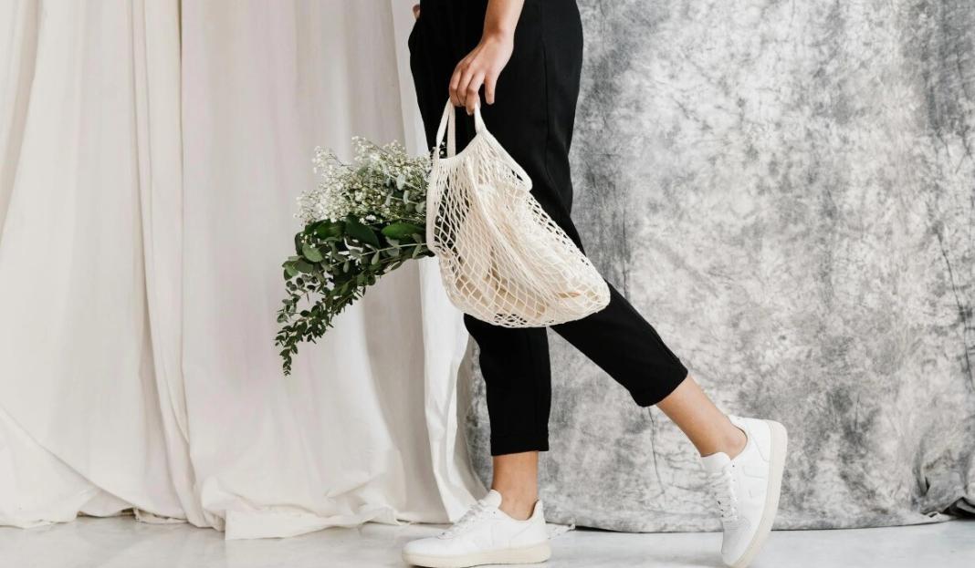 a lady walking in a simple dress, a bag with flowers signifying zero waste fashion