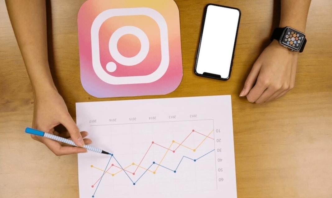 a person writing down notes in a sheet of paper near a mobile phone and having an Instagram logo 