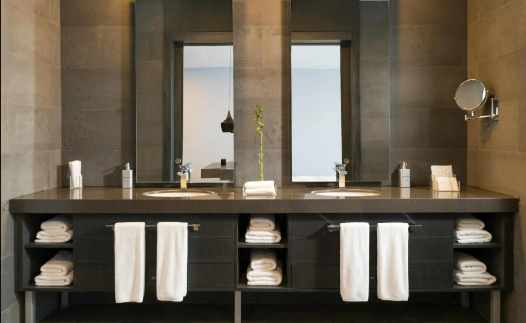 a clean bathroom with washing facility, tissue papers and mirrors