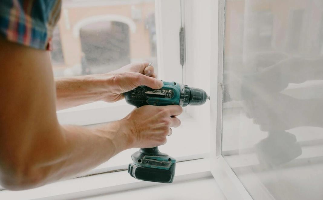 a person doing home repair on the glass window of his home
