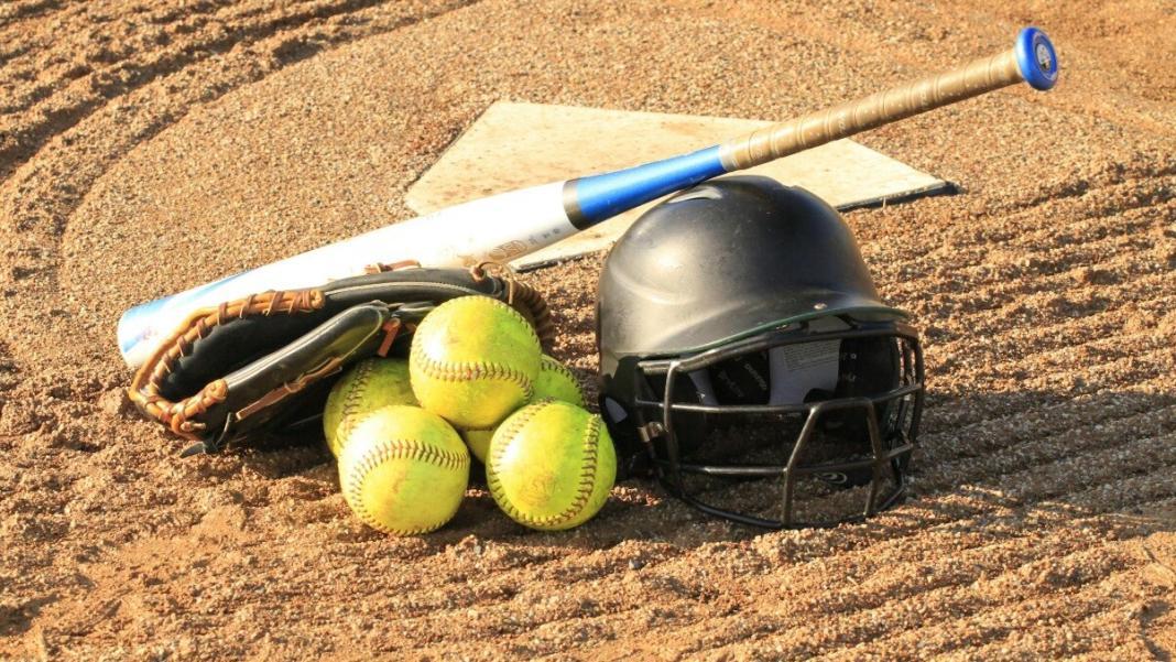 a few softballs and a bat placed on the ground