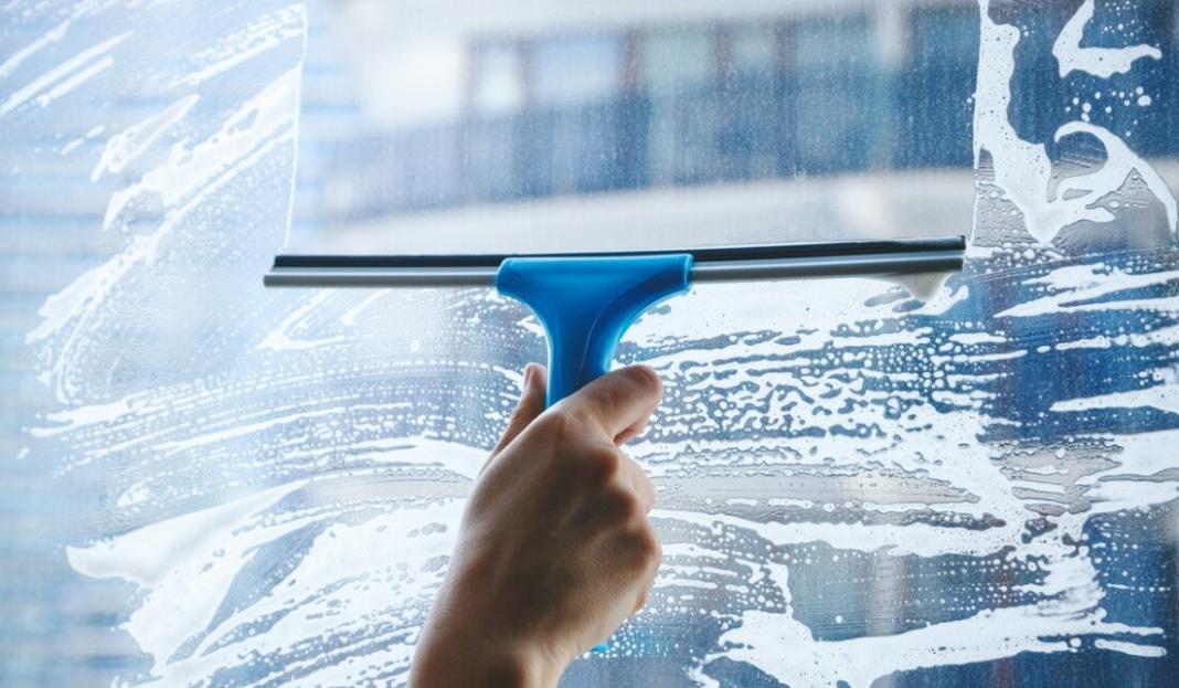 a person cleaning the window with soap solution to make it clean