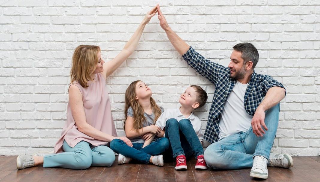 a father, a mother and two kids in front of their house wall