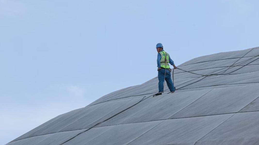 a person walking on the roof top of a high rise building and performing work at height