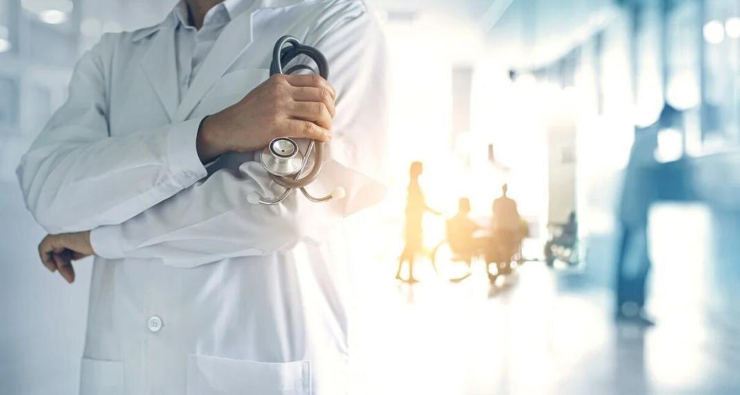 a medical practitinoer folding his hands and a hospital background 