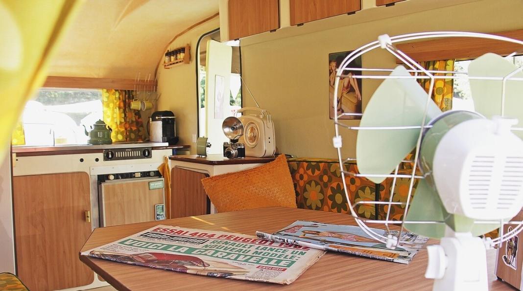 inside of a caravan having a fan, newspaper, radio and the picture of a lady