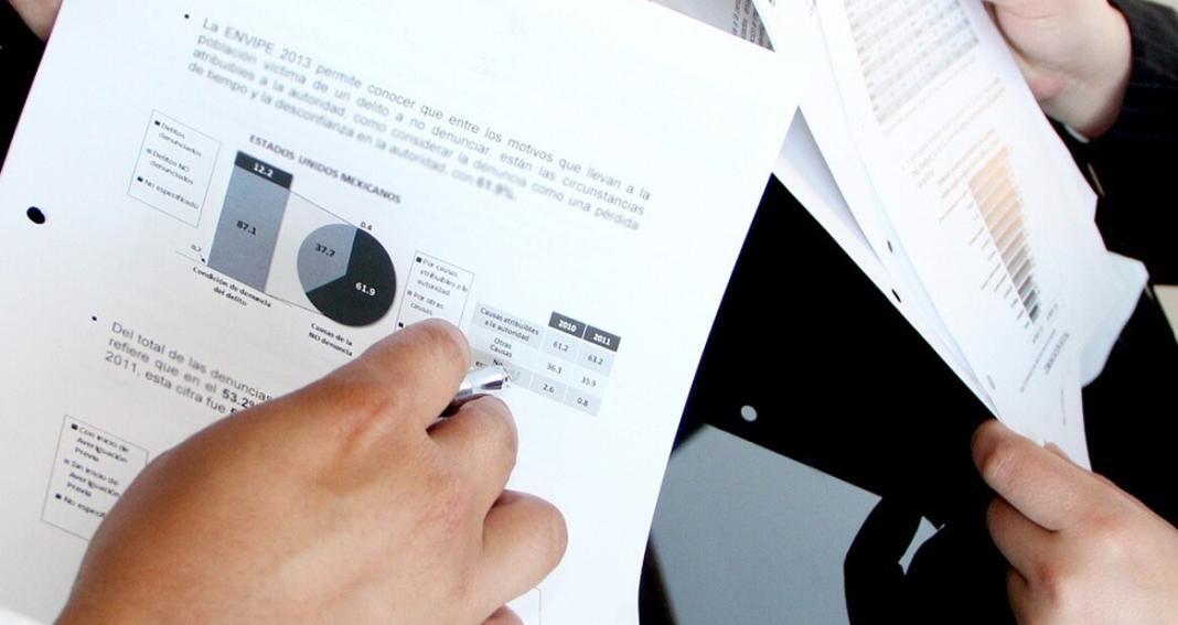 persons holding sheets of paper having chart data information for data analysis