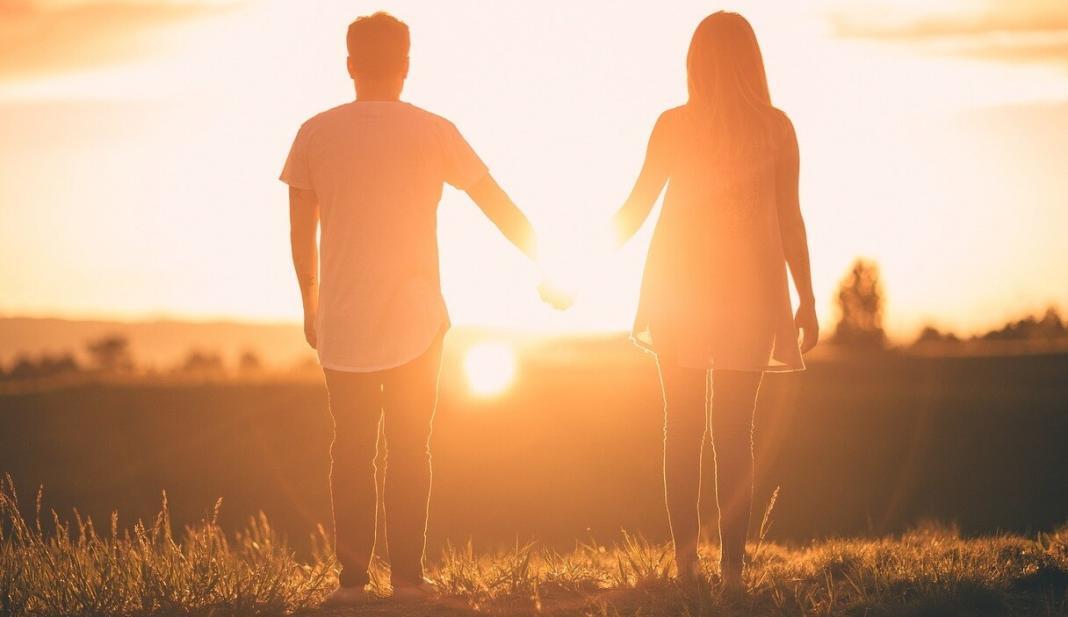 a lady holding the hand of a man during sunset showing love in relationships