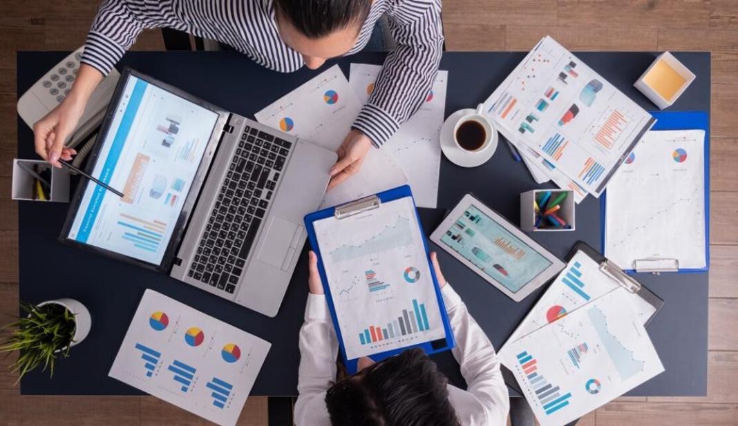 different papers with chart and table diagrams lying near the laptop