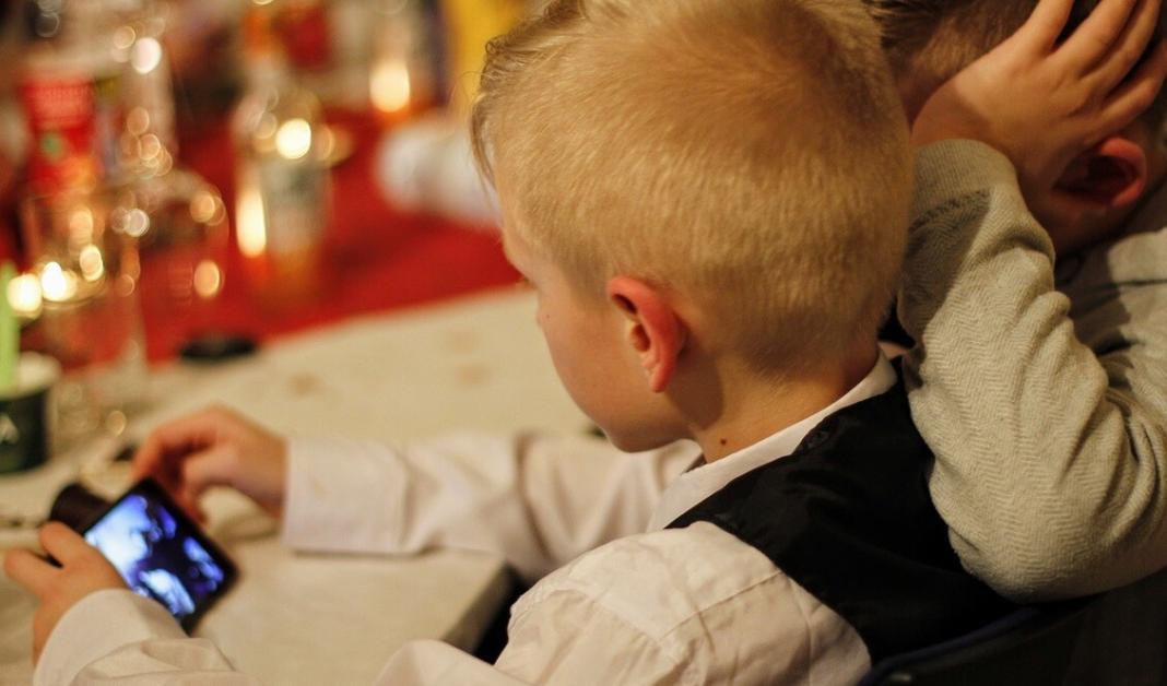 two children well dressed looking at a mobile phone