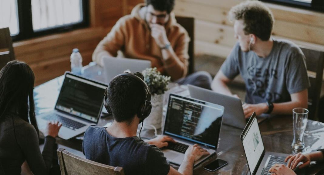 a group of people sitting around a table discussing software solutions