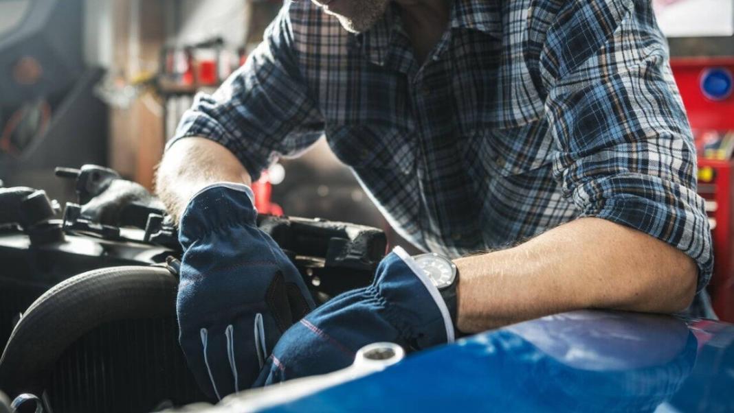 a person wearing gloves is seen repairing the front of a car 