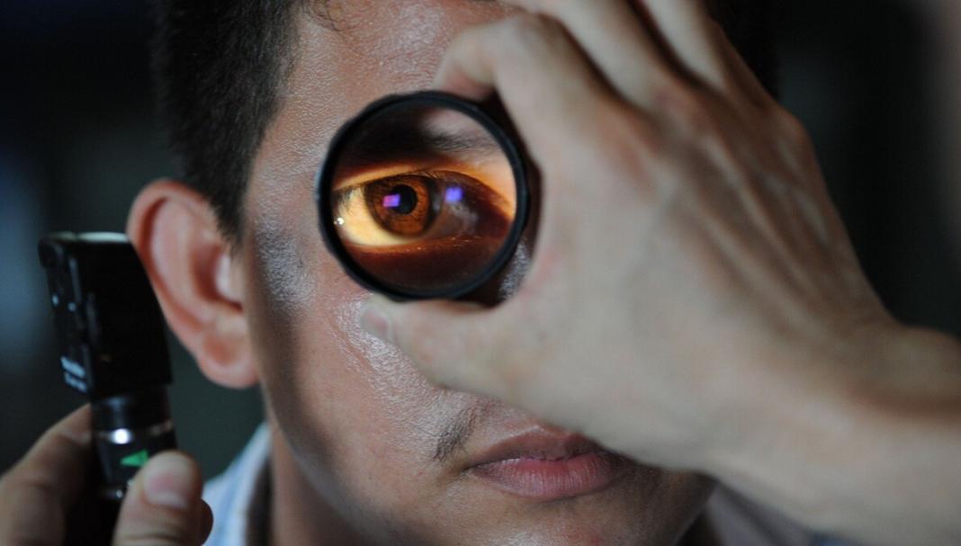 a person is testing his eye using a lens by an eye doctor