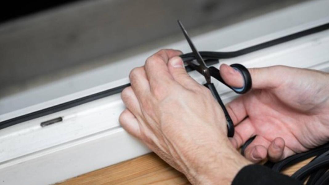 a person cutting the rubber strips of the window using a scissor