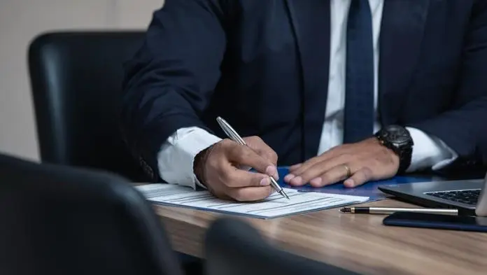 a lawyer writing with his pen on a sheet of paper placed on a table