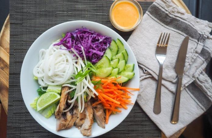 vegetables placed inside a white plate with fork and spoons beside on a table