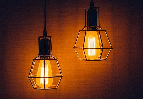 two bulbs placed inside a house with orange plain background