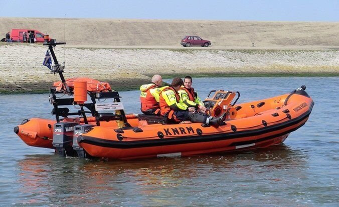 3 persons on a coast guard boat sailing through water