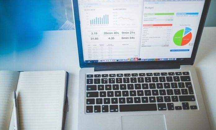 data analytics view seen in a laptop placed on a table with charts and graphs