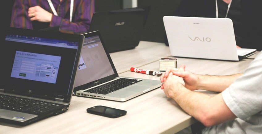 persons sitting around a table with laptop discussing financial planning