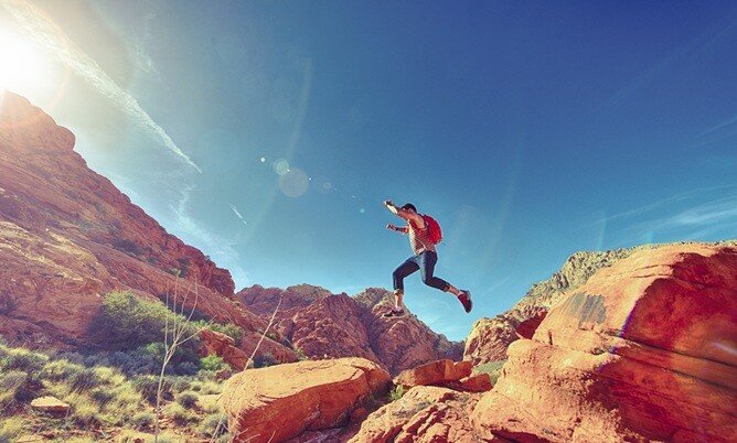 a man with his backpack jumping and hiking in the mountains in Denver