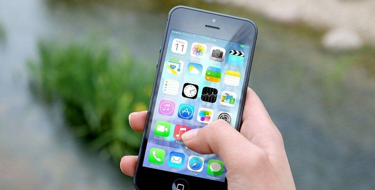 a person holding a mobile with a number of apps present on the screen
