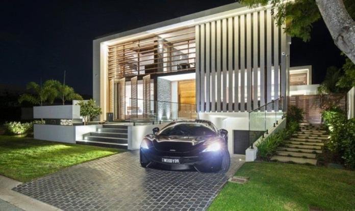 car parked on a pavement in front of a modern house with lights on