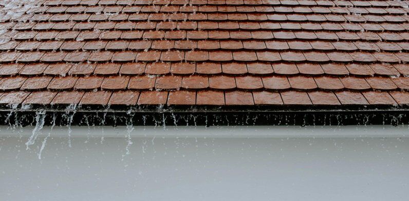 rainwater flowing on roof top with gutter passage at the edge