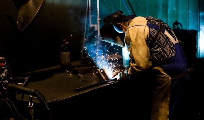 a person working on a welding part using a welding machine on steel