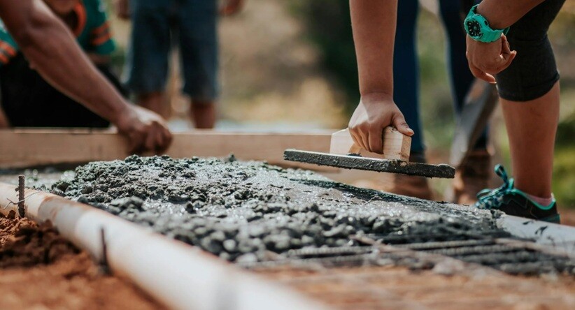 cement and concrete being laid down by persons on top of the bricks