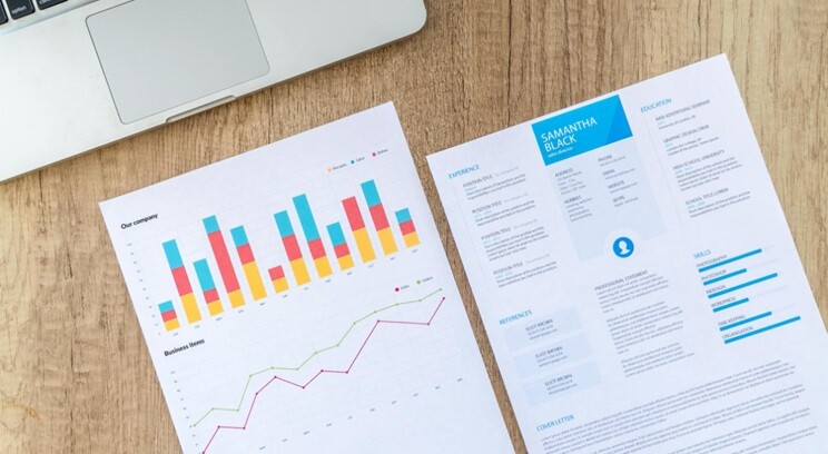 a resume lying on a table with an analytical report beside along a laptop